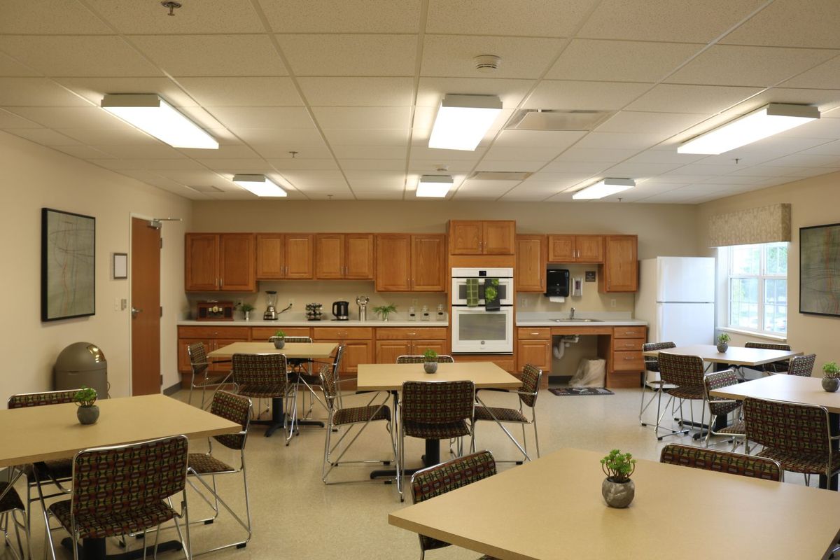 A spacious break room with tables and chairs, featuring kitchen amenities.