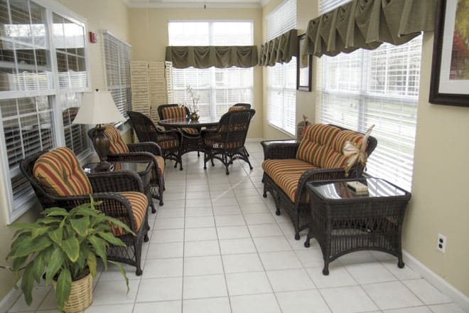A cozy sunroom with wicker furniture and ample natural light streaming through large windows.