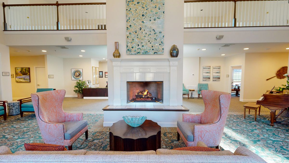 A cozy living room with a fireplace, armchairs, and decorative elements.
