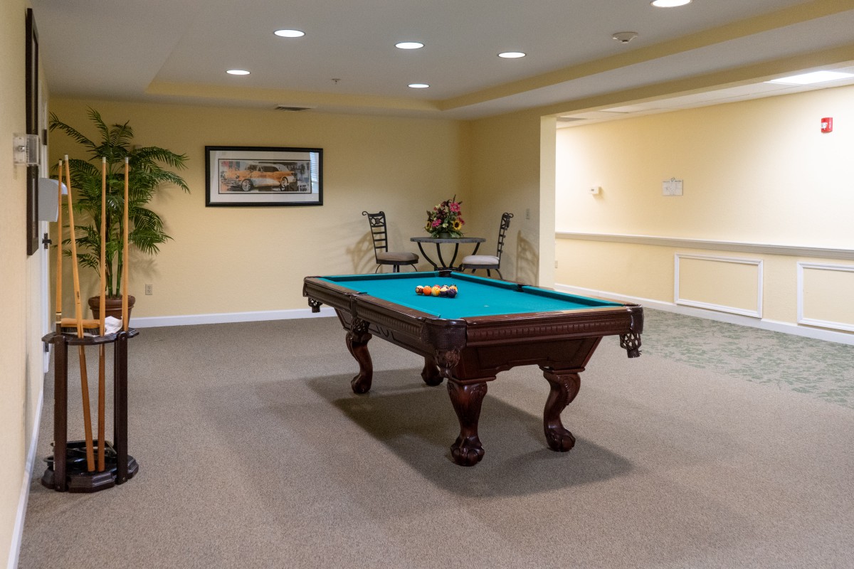 A well-lit game room featuring a classic pool table and seating area.