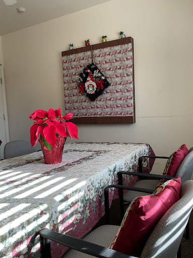 A beautifully decorated dining room with a festive table setting, featuring a poinsettia centerpiece and a holiday wreath on the wall.