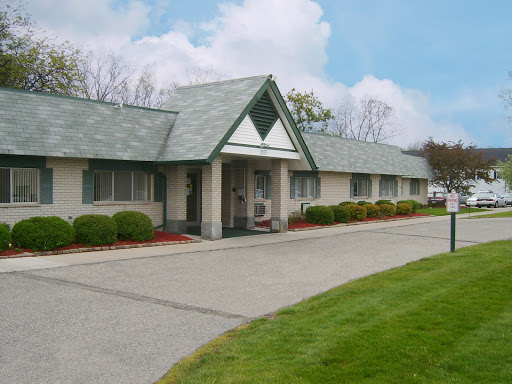 A well-maintained single-story building surrounded by a neatly trimmed lawn and a clear blue sky.