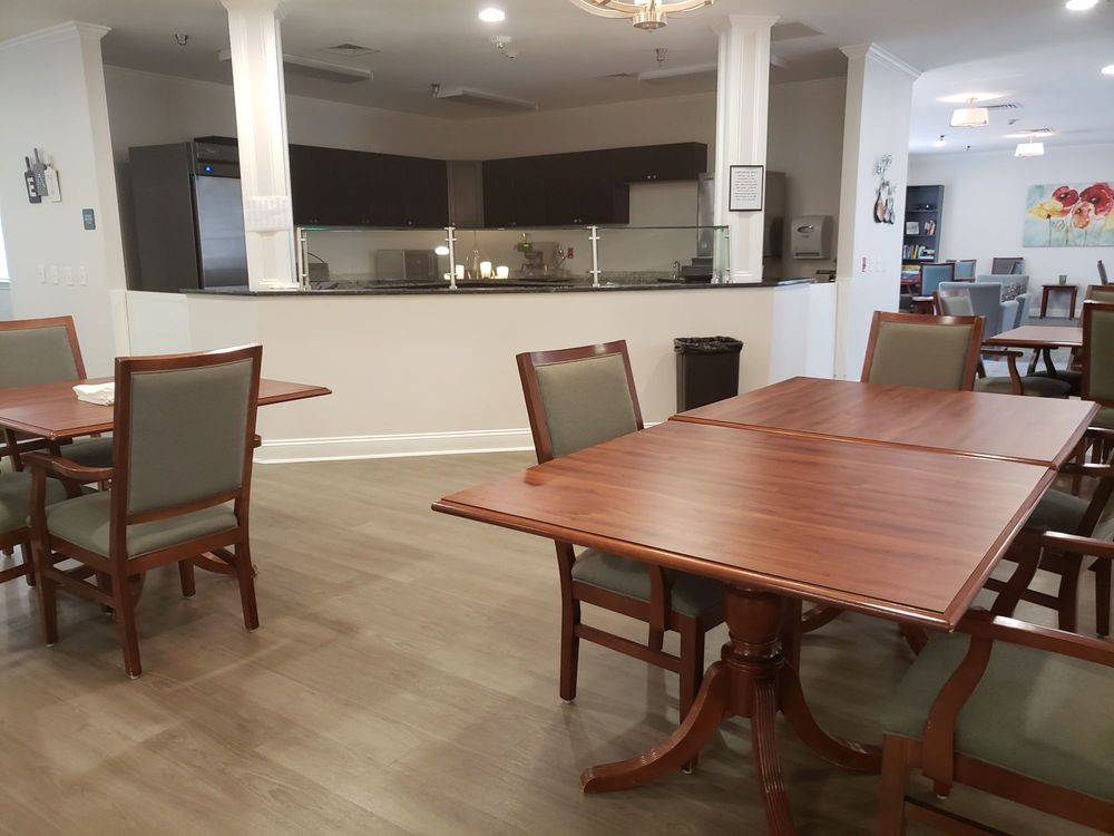 Spacious dining area with wooden tables and chairs, adjacent to a modern kitchen.