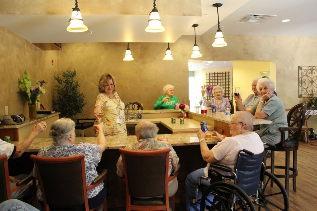 A group of seniors socializing around a bar-like setting indoors.