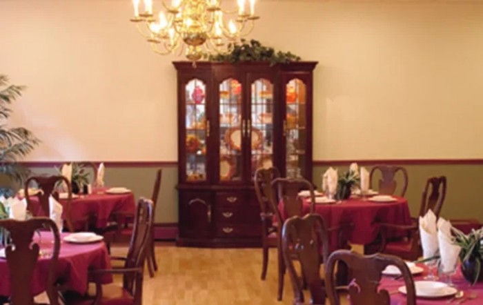 A warmly decorated dining room with a chandelier and china cabinet.