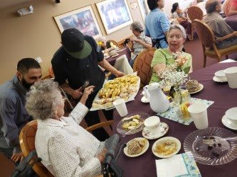 Seniors enjoying a meal together with a selection of pastries being served.
