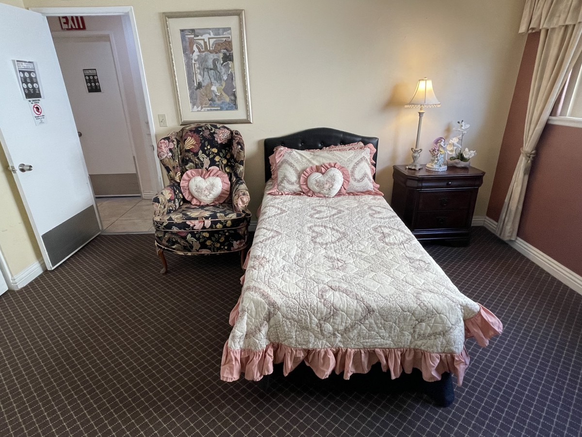 A cozy bedroom with a floral-themed decor, featuring a single bed, matching chair and nightstand.
