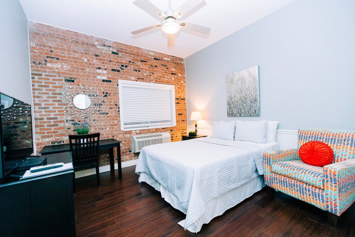 A stylish bedroom with a brick accent wall and modern furnishings.
