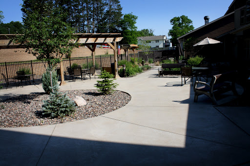 A serene outdoor space featuring a winding pathway surrounded by greenery and seating areas.