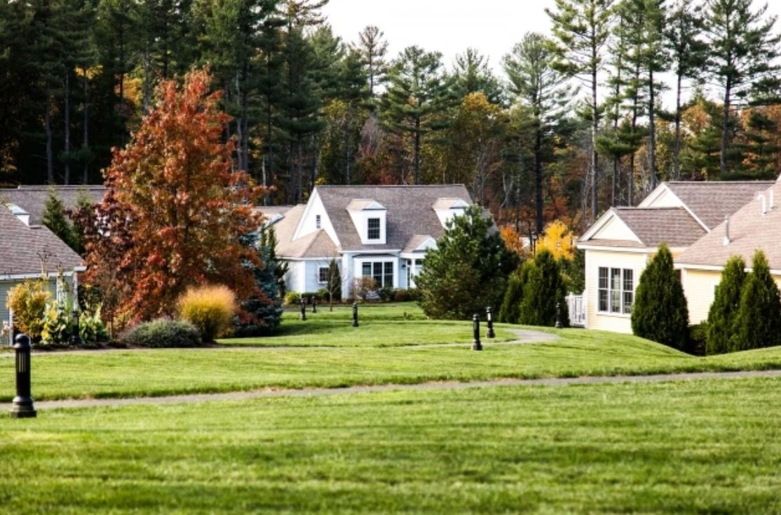A suburban home with a well-maintained lawn and colorful autumn trees.
