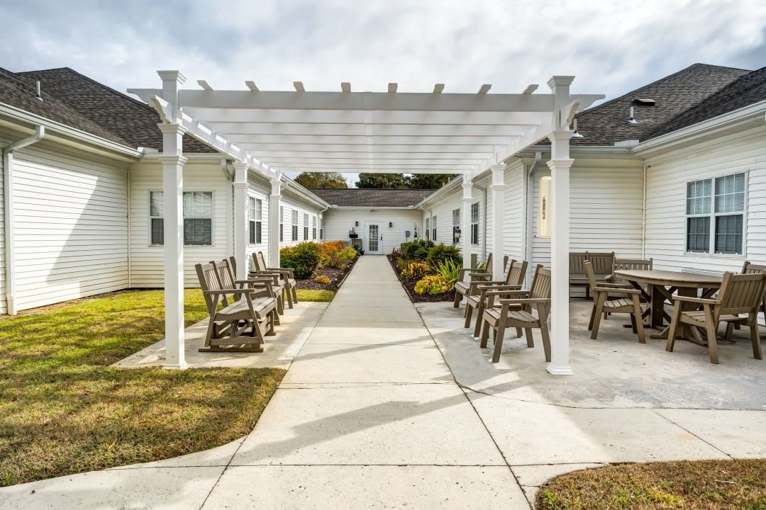 A walkway with a pergola, surrounded by outdoor seating and landscaped gardens.