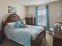 A cozy bedroom with a wooden bedframe, decorated with blue and white bedding and accents.
