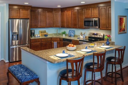 A modern kitchen featuring wooden cabinetry, granite countertops, and a cozy dining area with bar stools.