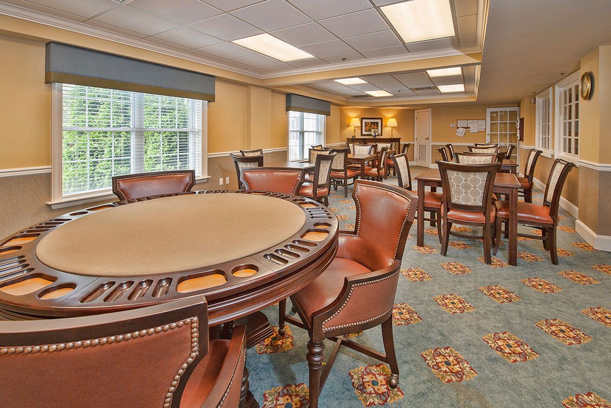 A well-lit game room featuring a poker table and chairs, with windows allowing natural light to enter.