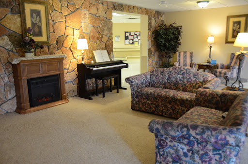 A cozy living room featuring floral-patterned sofas, a piano, and a decorative stone wall.