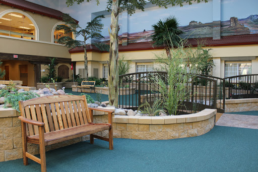 A serene indoor pool area surrounded by tropical plants and a wooden bench for relaxation.