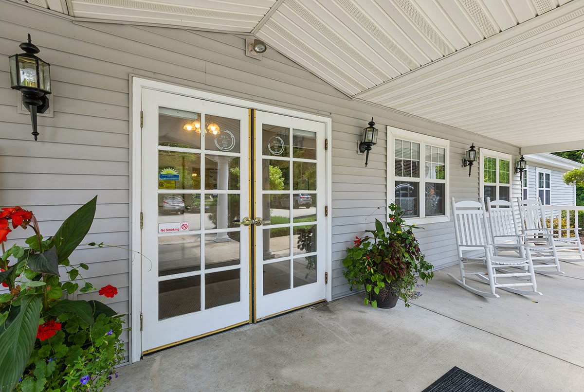 A welcoming entrance with glass double doors, potted plants, and a covered porch.