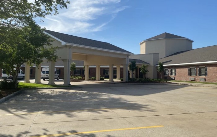 A commercial building with a covered driveway and parking area on a sunny day.