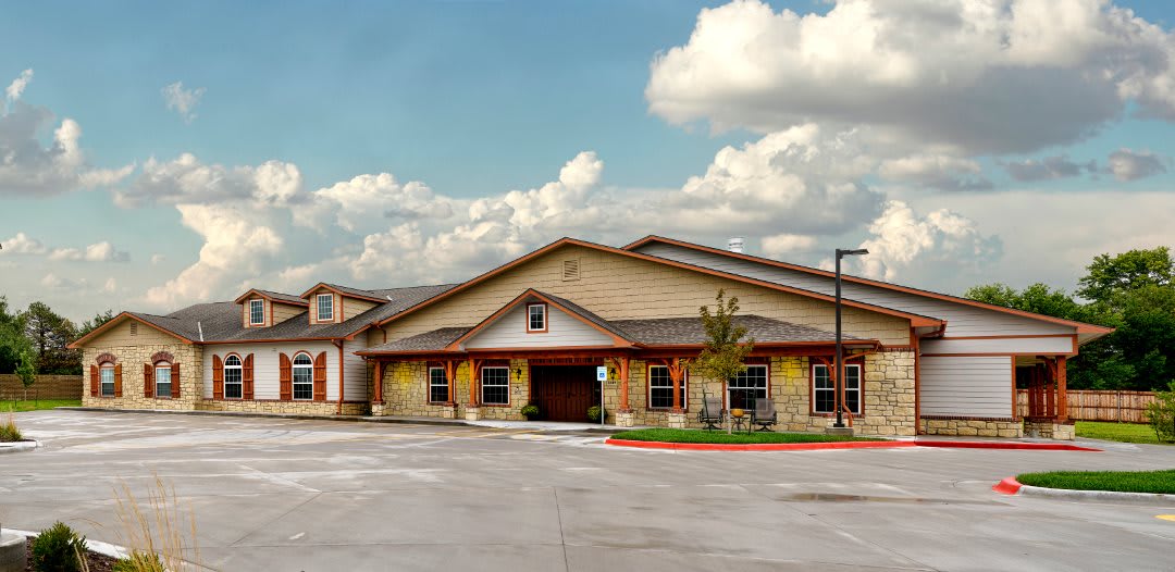 A modern building with a spacious parking lot under a cloudy sky.