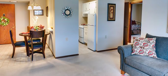 A cozy apartment interior featuring a view into the kitchen with white cabinets and appliances.