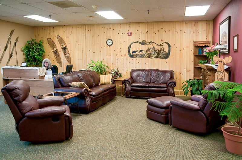 A cozy lobby with leather sofas, rustic wood paneling, and decorative elements.