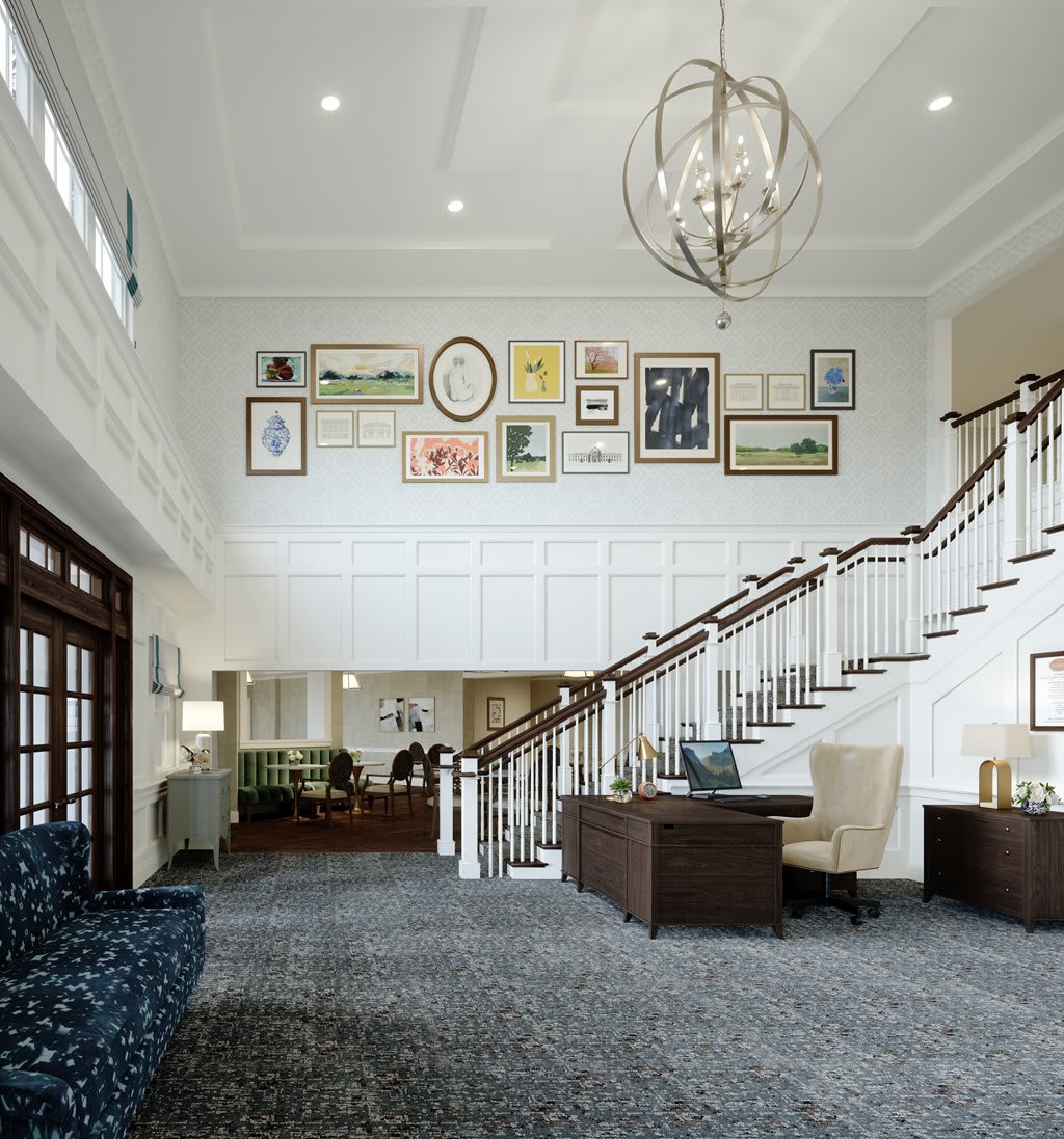 A spacious and elegantly designed lobby featuring a staircase, art on the walls, and modern furniture.