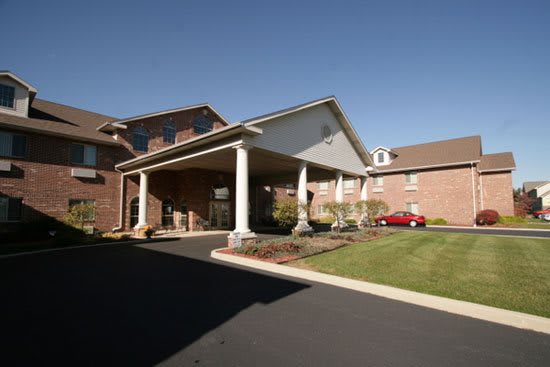A brick building with a covered entrance and landscaped surroundings.
