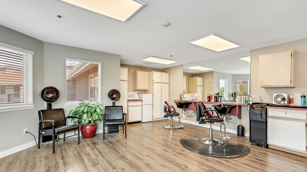 A modern hair salon interior with styling chairs, large mirrors, and bright lighting.