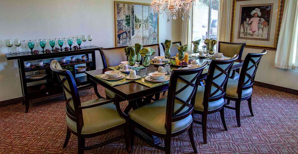 Elegantly set dining table with a chandelier overhead.
