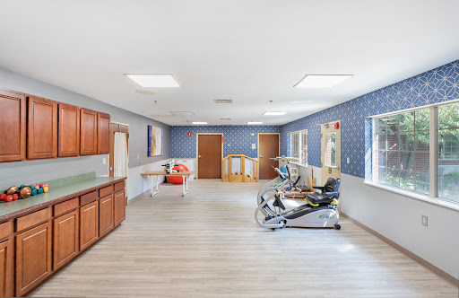 A spacious rehabilitation room featuring modern furniture and a calming blue color scheme.