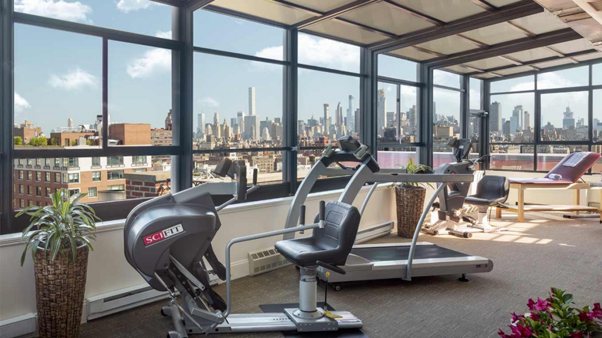 A gym with exercise equipment overlooking a city skyline.