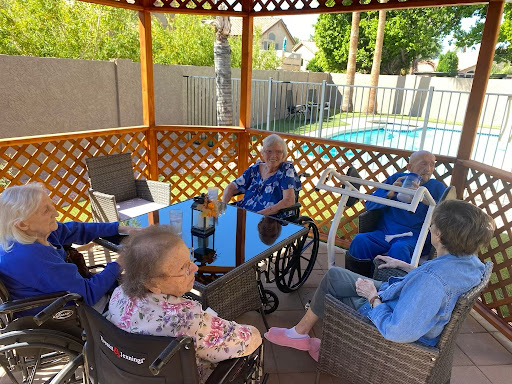 A group of seniors enjoying time together in a gazebo by the pool.