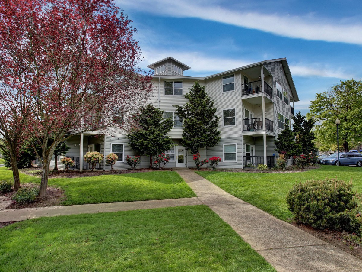 A residential apartment building surrounded by lush greenery and well-maintained lawns.