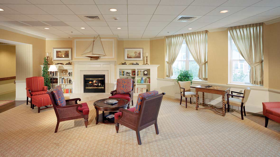 A cozy living room with a fireplace, armchairs, and bookshelves.