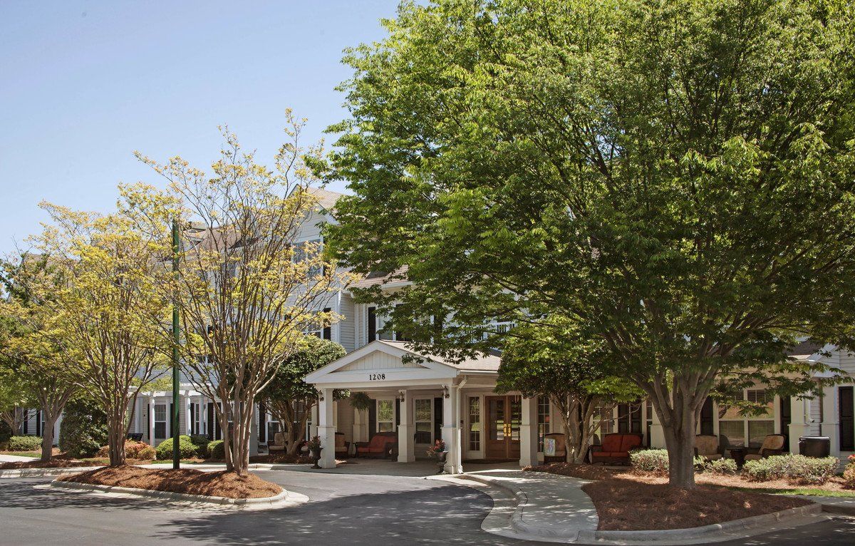 A view of a building entrance surrounded by trees and landscaping.