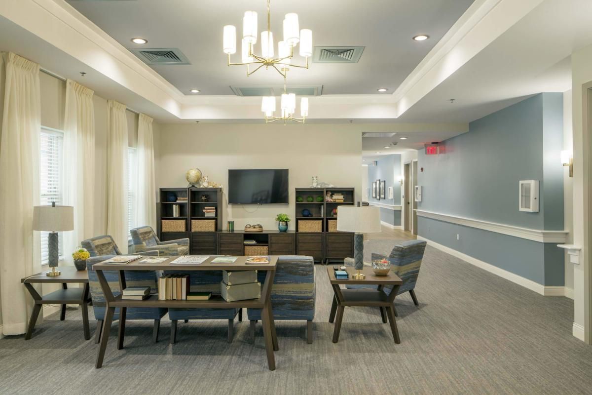 A modern living room with a seating area, TV, and chandelier lighting.