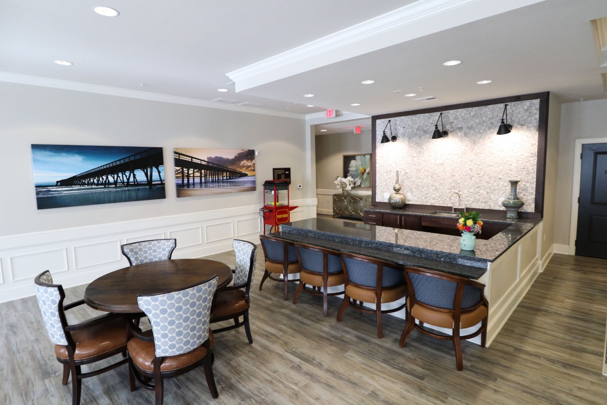 A modern and stylish kitchen-dining area featuring bar stools, a round dining table, and contemporary artwork on the walls.