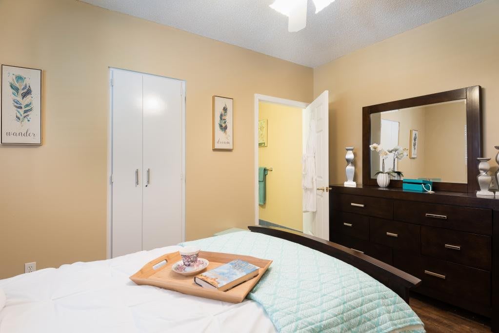 A cozy bedroom with a neatly made bed, wardrobe, and dresser with a mirror.