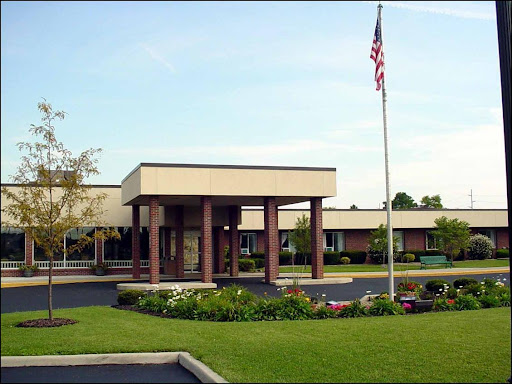 A well-maintained educational institution with vibrant landscaping and an American flag.