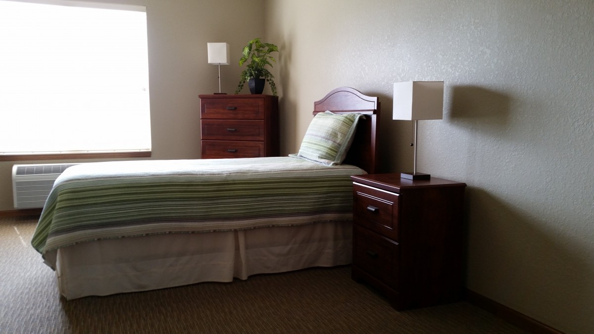 A minimalist bedroom with a single bed, nightstand, and dresser.