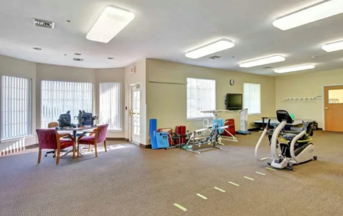 A well-equipped physical therapy room with exercise machines and seating areas.