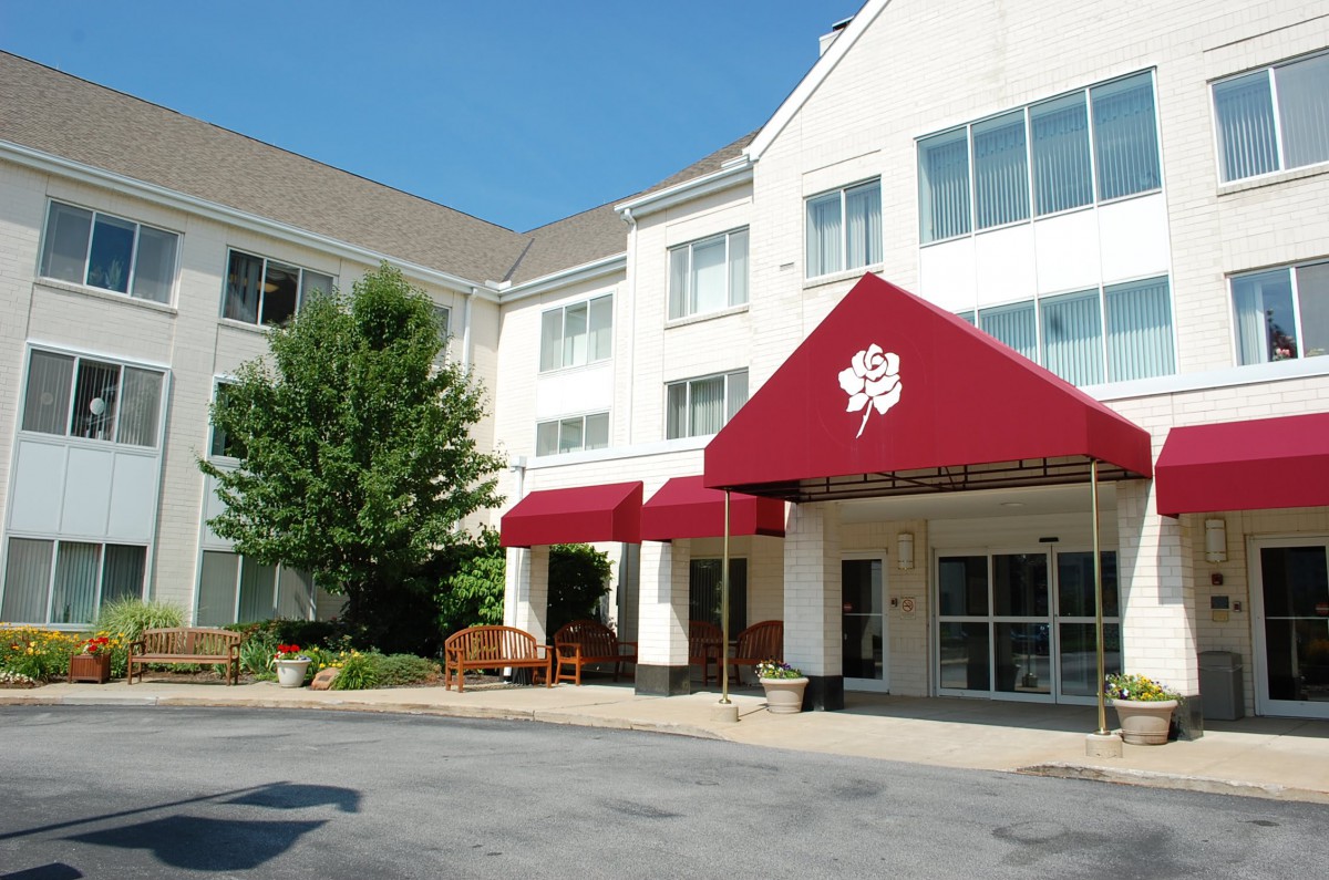 The entrance of a hotel with a red awning under clear skies.