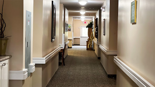 A well-lit hallway with carpet flooring, featuring walls adorned with artwork.