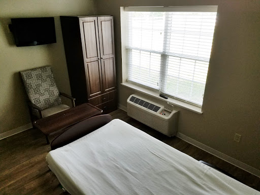 A cozy room featuring a bed, a comfortable chair, and natural light from the window.