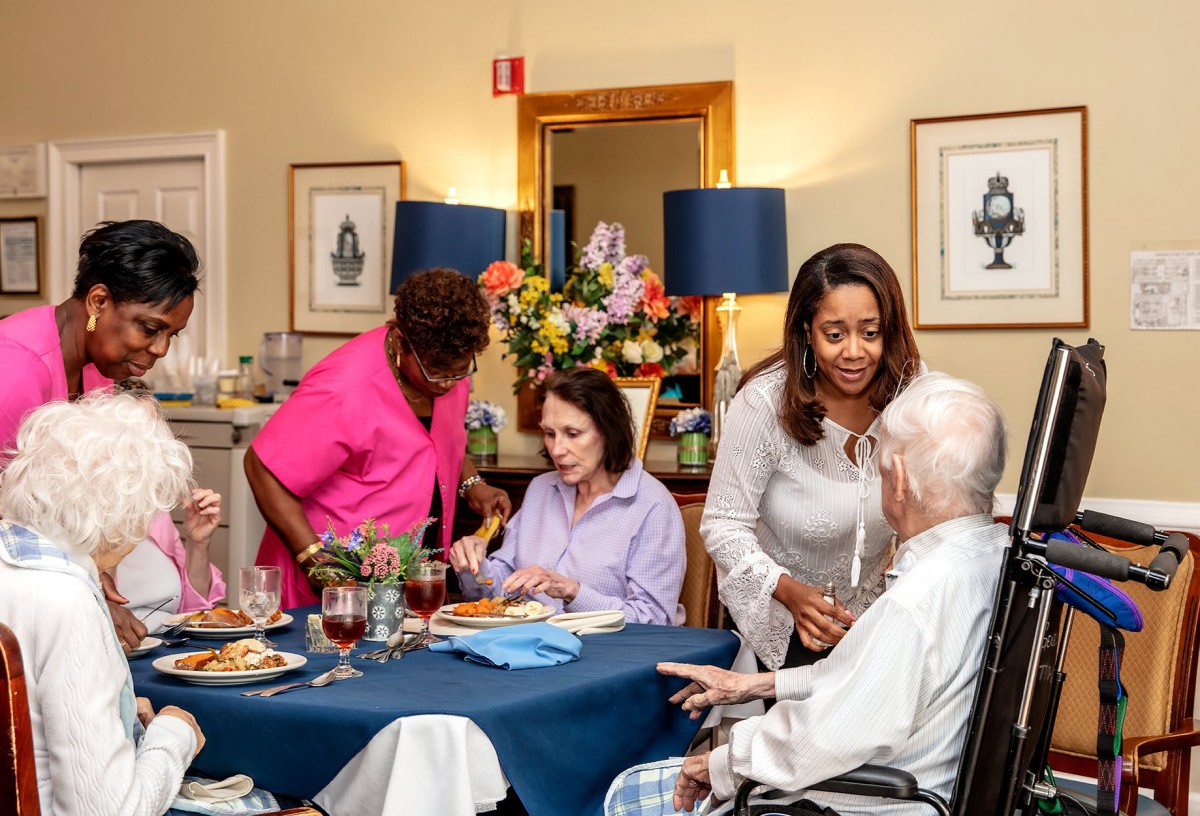 Caregivers assist seniors during a mealtime at a nursing home, fostering a warm and supportive environment.