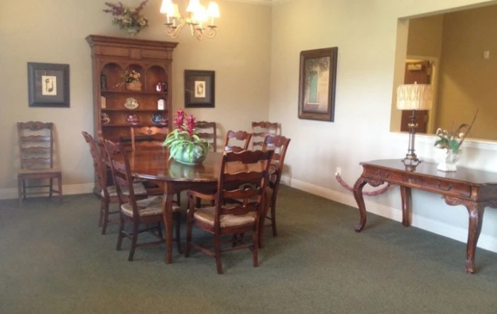 A cozy dining room with a wooden table, chairs, and a bookshelf in the background.