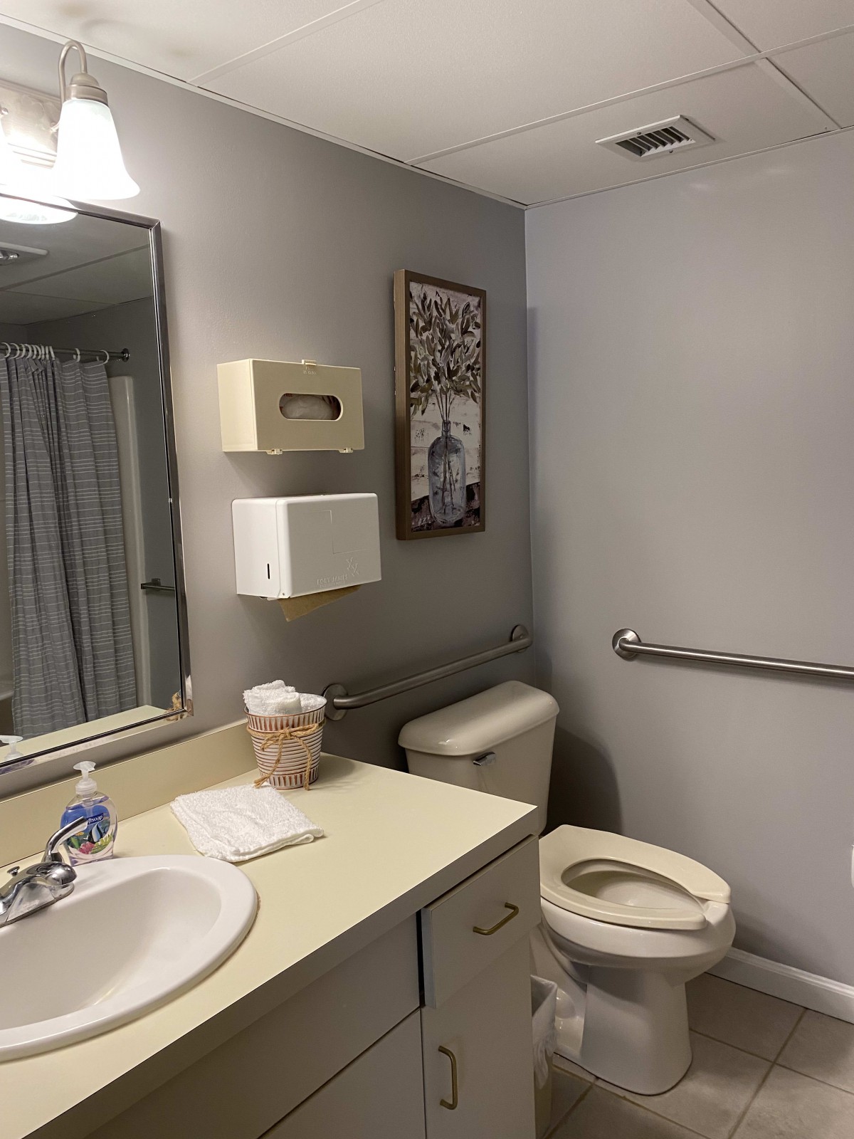 A well-organized bathroom with a sink, toilet, and handrail.