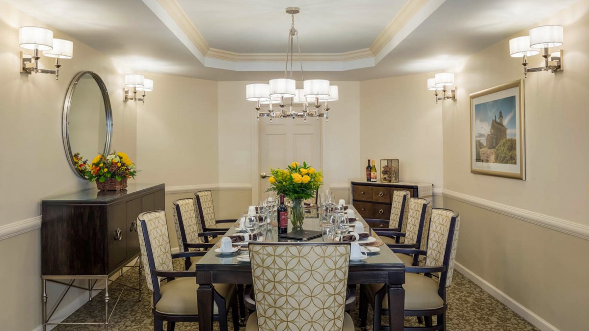 An elegantly set dining room with a long table, chairs, and ambient lighting.