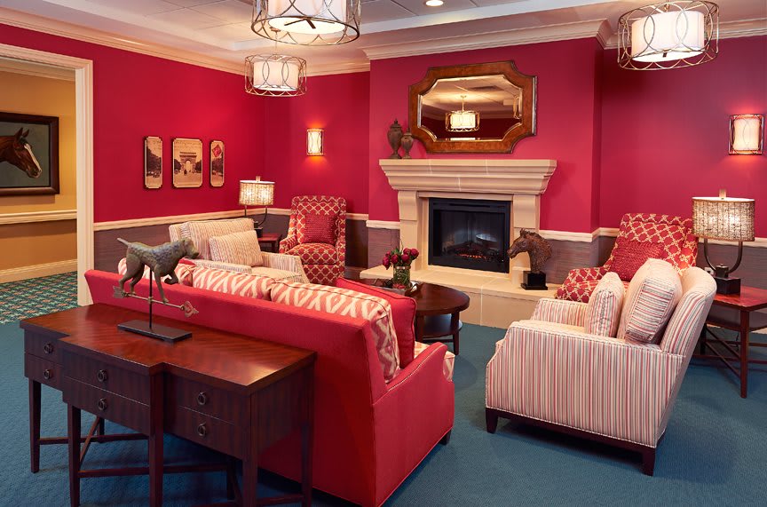 A cozy living room with vibrant red walls, featuring a fireplace, comfortable seating, and elegant decor.