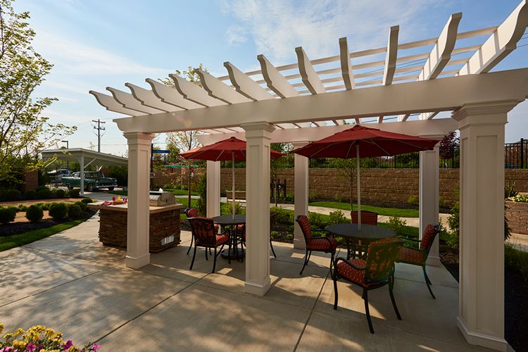 A patio area with a pergola providing shade to outdoor seating which includes tables and chairs.